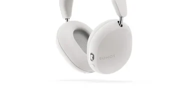 Sonos Ace Wireless Active Noise Canceling Over-Ear Headphones in white next to the Sonos Arc Premium Smart Soundbar, displayed on a minimalist living room console, highlighting sleek design and premium home audio setup.